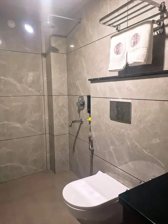 Shower area with marble tiling and a glass partition