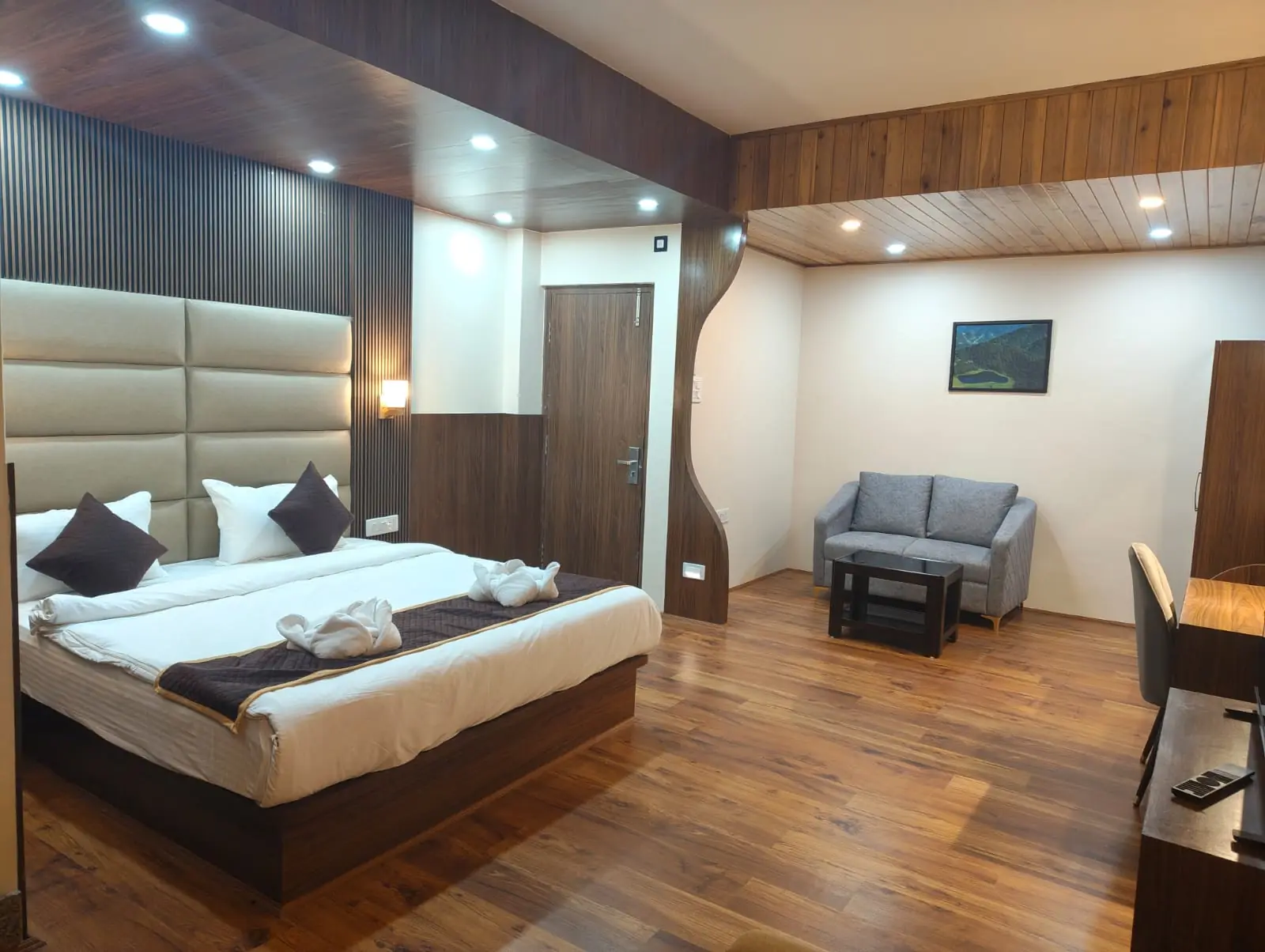 Deluxe room with a double bed, sofa and polished wooden flooring