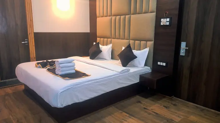 Close view of a made bed with folded towels and side lamps