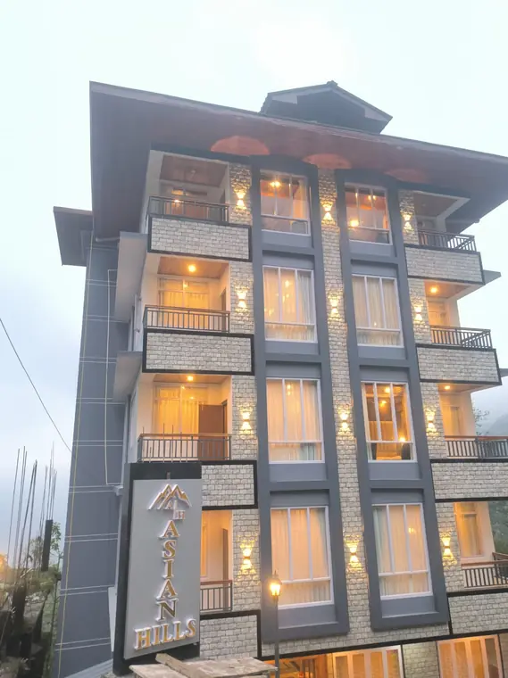 Hotel Asian Hills lit up at dusk, balconies glowing on every floor