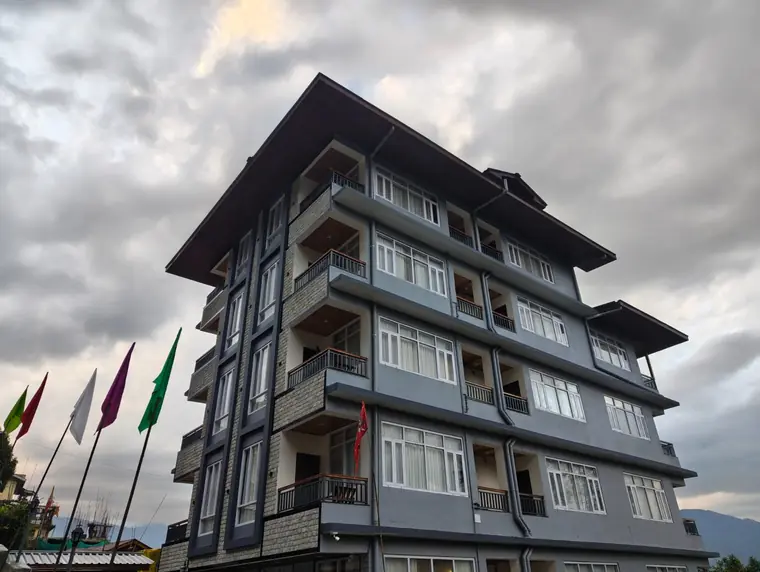 The hotel exterior with prayer flags in front under a cloudy sky